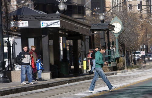 Al Hartmann  |  Tribune file photo
A pedestrian crosses Main Street and train tracks mid-block at the Gallivan TRAX station near 300 South in Salt Lake City. The Utah Transit Authority will start writing tickets for 