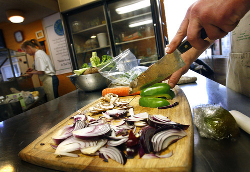 Scott Sommerdorf  |  The Salt Lake Tribune             
Volunteer Damien Gray chops up some vegetables while Theresa Fox works in the kitchen at the One World Cafe, Friday, March 23, 2012. Occupy SLC maintains a tent presence at Gallivan Center but cannot have a kitchen there, so many of them eat and volunteer at One World Cafe. Occupiers have started a community garden behind the Cafe to help contribute fresh food.