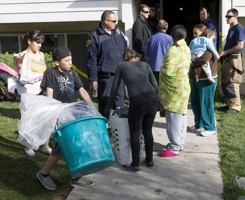 Al Hartmann  |  The Salt Lake Tribune
Salt Lake City Fire Department members and police allow some of the 140 displaced renters to remove clothes and valuables Thursday morning from their smoke-damaged apartment building at 400 North and Redwood Road. Fourteen units sustained smoke damage from last night's fire and utilities had to be shut off for the entire apartment unit.