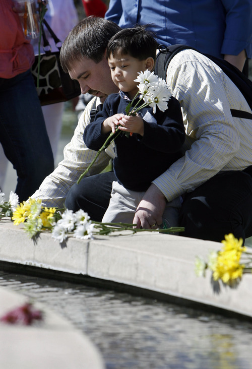 Francisco Kjolseth  |  The Salt Lake Tribune
Placing flowers, Brian Hoopes of Taylorsville stays close his son Patrick, 3, who is tethered to him for his intravenous fluids since he was essentially born without intestines. On Wednesday, April 4, 2012, Patrick ceremoniously started the Celebration of Life Monument fountain on Library Square in Salt Lake which is dedicated to those who have given the gift of life through organ, eye, tissue and blood donation. Patrick has been on the donor list for a small intestine for three years.