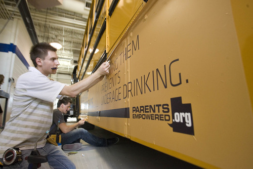 Paul Fraughton | The Salt Lake Tribune.
Daniel Johnson,front, and Jaren O' Farrell, of Wrap Star  put the finishing touches on an ad they placed on a Jordan District school bus. The district had the ad  put on four of their buses  with plans to do more.  Money generated from the ads  will stay in the transportation dept.The district will review all advertising, making sure it complies  with guidelines  they established.
 Tuesday, April 24, 2012