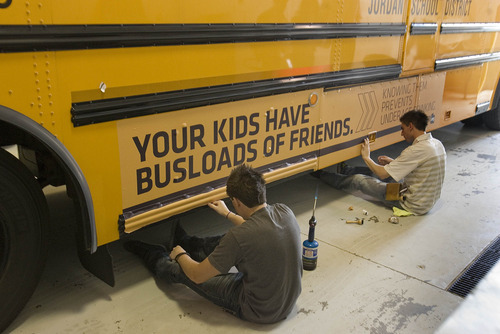 Paul Fraughton | The Salt Lake Tribune.
Daniel Johnson,right,  and Jaren O' Farrell, of Wrap Star  put the finishing touches on an ad they placed on a Jordan District school bus. The district had the ad  put on four of their buses  with plans to do more.  Money generated from the ads  will stay in the transportation dept.The district will review all advertising, making sure it complies  with guidelines  they established.
 Tuesday, April 24, 2012