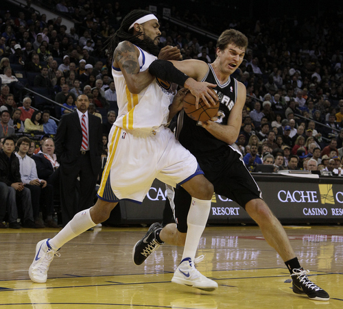 San Antonio Spurs center Tiago Splitter (22), from Brazil, right, tries to control the ball next to Golden State Warriors center Mikki Moore (31) during the third quarter of an NBA basketball game in Oakland, Calif., Monday, April 16, 2012. (AP Photo/Jeff Chiu)