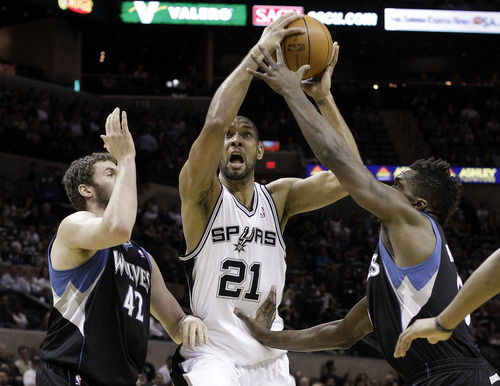 San Antonio Spurs' Tim Duncan (21) is defended by  Minnesota Timberwolves' Kevin Love (42) and Martell Webster (5) during the first quarter of an NBA basketball game on Wednesday, March 21, 2012, in San Antonio. (AP Photo/Eric Gay)