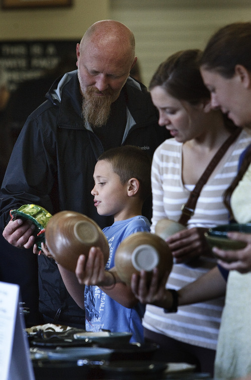 Leah Hogsten  |  The Salt Lake Tribune
Jason Williams of Bountiful looks at writing on a bowl made by a fourth grader that his grandson Brock Jones, 7, wanted him to see. Local artists from Clay Arts Utah handmade hundreds of  glazed pottery bowls to help feed the hungry via proceeds going to Catholic Community Services. at St. Vincent de Paul Resource Center, on Saturday in Salt Lake City