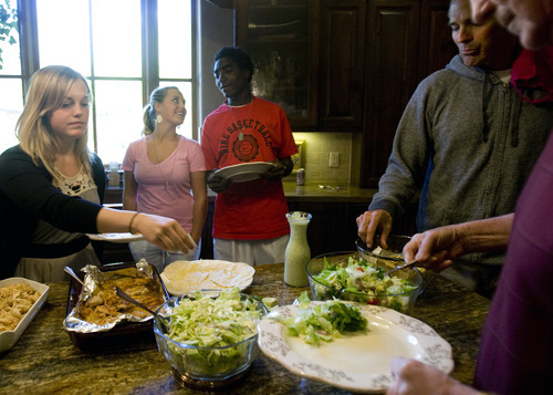 Kim Raff | The Salt Lake Tribune
Kofi Johnson talks with his sister Kelsey Johnson as people fill their plates during dinner in their house in Alpine, Utah on May 6, 2012. Kofi Johnson is a Ghanan orphan who was adopted by the family of former NFL kicker/punter Lee Johnson. The 18-year-old Lone Peak soccer player has struggled to adapt to American customs and the spirit of family, but thanks to the efforts of his new mother, Shelley, they are coming together and creating an unexpected recipe for hope.