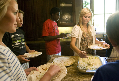 Kim Raff | The Salt Lake Tribune
Kofi Johnson serves himself dinner with his family members in their house in Alpine, Utah on May 6, 2012. Kofi Johnson is a Ghanan orphan who was adopted by the family of former NFL kicker/punter Lee Johnson. The 18-year-old Lone Peak soccer player has struggled to adapt to American customs and the spirit of family, but thanks to the efforts of his new mother, Shelley, they are coming together and creating an unexpected recipe for hope.