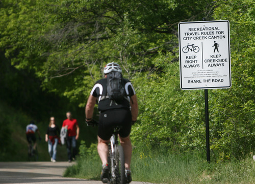 Kim Raff | The Salt Lake Tribune
People walk and bike past one of the new signs on the City Creek Trail for bikers and pedestrians in Salt Lake City, Utah on May 25, 2012.