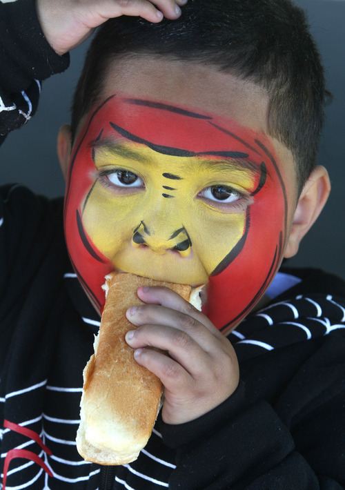 Rick Egan  | The Salt Lake Tribune 

Four-year-old Soni Vainuku, West Valley,  enjoys his free hot dog, after having his face painted at the Valley View cemetery in West Valley, Monday, May 28, 2012. Valley VIew Cemetery offers free hot dogs and sodas to people visiting their family's graves, as well as face painting.