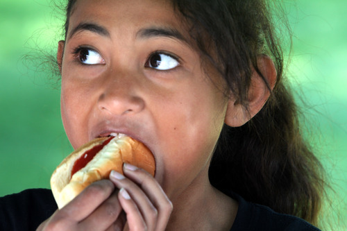 Rick Egan  | The Salt Lake Tribune 

Peti Manatau, 8, West Valley, enjoys a free hot dog at the Valley View cemetery in West Valley, Monday, May 28, 2012. Valley VIew Cemetery offers free hot dogs and sodas to people visiting their family's graves, as well as face painting.