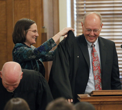 Al Hartmann  |  The Salt Lake Tribune 
David Nuffer is helped into his new judicial robe by wife Lori after he was sworn in as a U.S. District Court Judge at the Frank Moss Federal Courthouse in Salt Lake City on Tuesday, May 29.