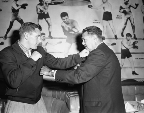 Daniel Hodge, left, the Olympic Wrestler and Golden Gloves Heavyweight champ who announced he has turned professional fighter, squares off with former Heavyweight Champion Jack Dempsey at a luncheon honoring Hodge, May 12, 1958, New York. (AP Photo)
