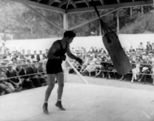 Heavyweight boxer Jack Dempsey punches the heavy bag as spectators watch at his training camp at Saratoga Lake, N.Y., on July 6, 1927.  (AP Photo)