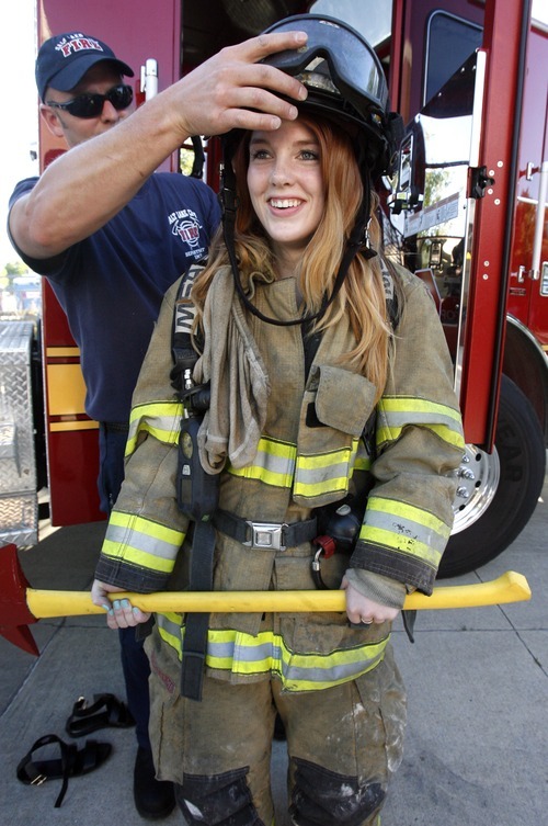 Rick Egan  | The Salt Lake Tribune 

Salt Lake City fire fighter, Ryan McAfee helps Mia Chase try on some fire fighter gear at the safety fair at Fire Station #7, near the Utah State Fairgrounds, Friday, June 1, 2012.