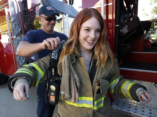 Rick Egan  | The Salt Lake Tribune 

Salt Lake City fire fighter, Ryan McAfee helps Mia Chase try on some fire fighter gear at the safety fair at Fire Station #7, near the Utah State Fairgrounds, Friday, June 1, 2012.