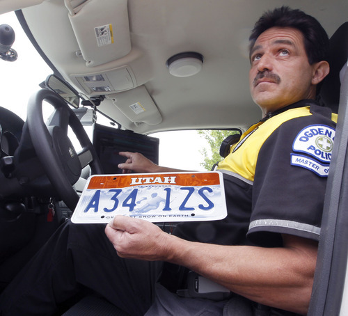 Al Hartmann  |  The Salt Lake Tribune 
Ogden Police master officer Tim Shelstead pulls a license plate he will read in a demonstation on a specially equipped Ogden police car that can read license plates in real time.  	Agencies around the state are using license plate scanners to aid highway and street patrol cars in apprehending criminals.   They can determine if the car's registration and insurance is up to date.