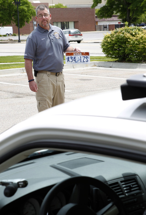 Al Hartmann  |  The Salt Lake Tribune 
Ogden Police crime analyst Dave Weloth holds a license plate up to be read by a specially equipped Ogden police car that can read license plates in real time.  	Agencies around the state are using license plate scanners to aid highway and street patrol cars in apprehending criminals.   They can determine if the car's registration and insurance is up to date.