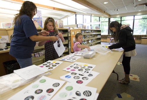 Paul Fraughton / Salt Lake Tribune
 As Angela Huerta, age 9, right, looks over the table of designs,Arlene Gallegos,left helps her daughter Samantha, age 12, and her granddaughter Elena Naranjo ,age 5, select designs to be made into buttons. The activity is one  the West Valley Library will feature in its summer reading program.

 Friday, May 25, 2012