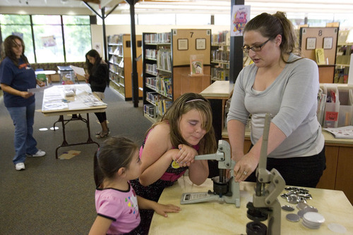 Paul Fraughton  |  Salt Lake Tribune
With the help of Melissa Wayman, teen services librarian at The West Vally City Library Smantha Gallegos, 12, pushes down on the lever to create her own button.The activity is one the West Valley Library will feature in its summer reading program.