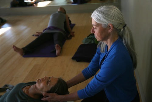 Kim Raff | The Salt Lake Tribune
Charlotte Bell helps Charlyn Raaberg into a position while leading a yoga class recently in Salt Lake City. Bell recently published a book called 