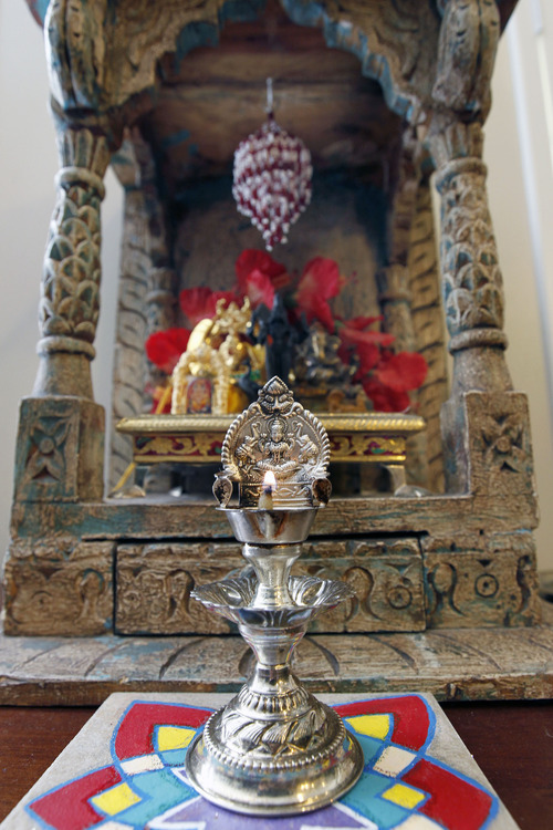 Al Hartmann  |  The Salt Lake Tribune 
A lighted candle and east-facing shrine are part of  a daily ritual in a Hindu home.