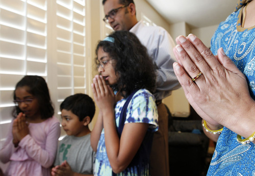 Al Hartmann  |  The Salt Lake Tribune 
Maha and Swathy Mahasenan, pray with their children Nithya, 8, Adithya, 4 and Shreya, 10, at the east-facing shrine in their living room.   The prayers are a daily ritual in their Hindu home.