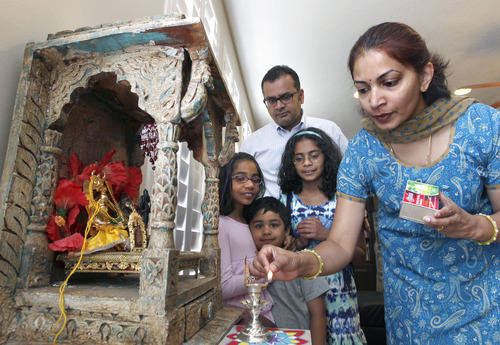 Al Hartmann  |  The Salt Lake Tribune 
Swathy Mahasenan, right, lights a candle in her home's east facing-shrine  with her husband Maha and children Nithya, 8, Shreya, 10, and Adithya, 4.   They perform the ritual every day in their Hindu home.