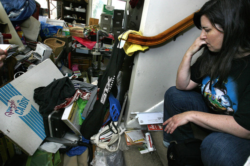 Scott Sommerdorf  |  The Salt Lake Tribune             
K Kay sits in the stairs near the front door - one of the only spaces she keeps clear. It's also the place where guests may sit when they visit the home. She is sitting there while describing specific items in one pile, and why she bought them, Thursday, May 24, 2012.