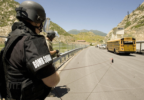 Paul Fraughton | The Salt Lake Tribune
Jeff Tracy of Provo Utah County Metro Bomb Squad and Ren Egbert, in black, of Salt Lake County Unified Fire Department, use ropes and pulleys to carefully remove a mock explosive device  from  a school bus, which  was used to simulate a passenger  airplane. This was one of eight scenarios faced by members of area bomb squads at a training exercise/competition held at  the Utah County Sheriff's Firearms Range near Thistle on Wednesday, June 13, 2012.