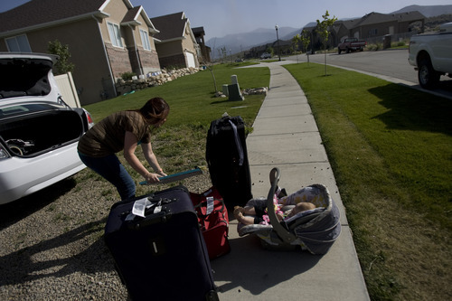 Kim Raff | The Salt Lake Tribune
Chelsea Coon unpacks her car while her daughter Lylah Coon sits in her car seat in Saratoga Springs, Utah on June 23, 2012. Coon was visiting her parents house when they were evacuated due to the Dump Wildfire in Saratoga Springs-Eagle Mountain.  Evacuated residents were able to return to their homes.