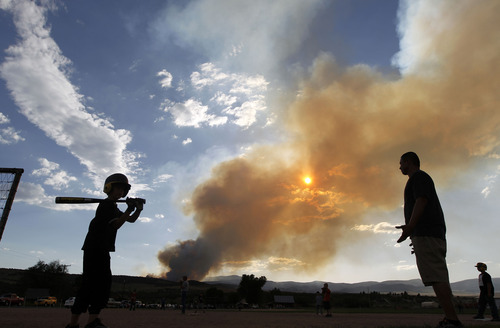Al Hartmann  |  The Salt Lake Tribune  
Life goes on in Fairview at the town ball park with little league games under a smoky sky from the Wood Hollow Fire west of town.