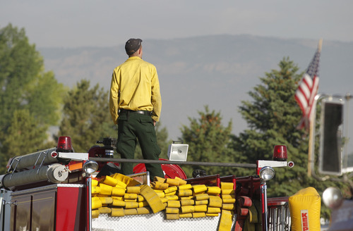 Al Hartmann  |  The Salt Lake Tribune  
Firefighter looks towards the mountain where the Wood Hollow fire  is burning Monday morning June 25.  
Wildland firefighters from multiple agencies gathered at the Moroni to Elementary School in Moroni  to organize and equip themsleves before going out to fight the Wood Hollow fire.