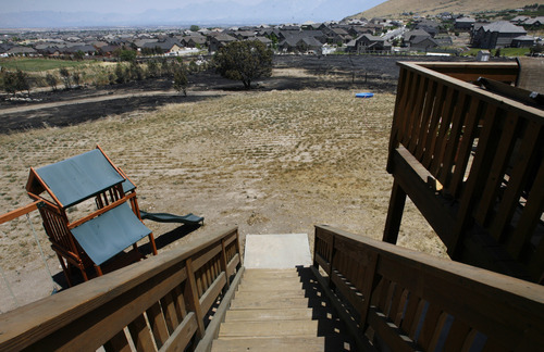 Scott Sommerdorf  |  The Salt Lake Tribune             
The fire was stopped just about 30 yards from the back of Chris Mitchell's parents home on Majestic Oaks Lane in Herriman, Sunday, July 1, 2012. He was ebulient with praise for firefighters who made a stand and stopped the fire from taking the home.