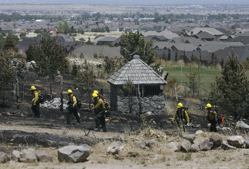 Scott Sommerdorf  |  The Salt Lake Tribune             
Fire crews searched for hot spots along the north edge of Chris Mitchell's parent's home on Majestic Oaks Lane in Herriman, Sunday, July 1, 2012.
