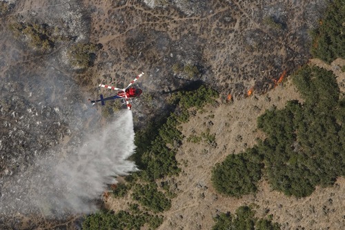 Leah Hogsten  |  The Salt Lake Tribune
A helicopter tries to drown out the fire line on the mountain behind Lambert Park. A wildfire that started about 2 p.m. Tuesday in Lambert Park in Alpine has burned at least one structure -- a barn -- and 80 homes have been evacuated, according to the Lone Peak Police Department. Utah County Sheriff's Sgt. Spencer Cannon said the fire was human-caused, somehow sparked by a man working on a trackhoe near the Alpine rodeo grounds.
Tuesday, July 3, 2012 in Alpine