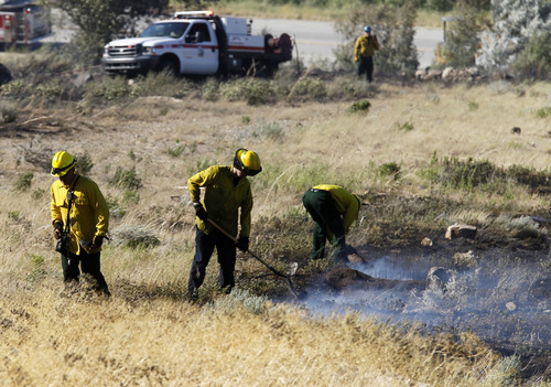 Al Hartmann  |  The Salt Lake Tribune
Ogden City fire fighters mop up and put out hot spots in field at the mouth of Ogden Canyon Tuesday morning July 3.  The fire came within a few feet of a condominium complex behind them to the east.