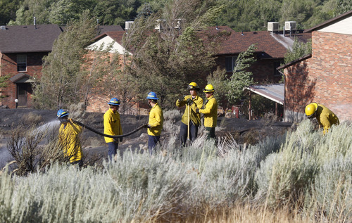 Al Hartmann  |  The Salt Lake Tribune
Ogden City fire fighters mop up and put out hot spots in field at the mouth of Ogden Canyon Tuesday morning July 3.  The fire came within a few feet of a condominium complex behind them to the east.