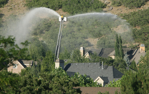 Steve Griffin | The Salt Lake Tribune
Firefighters spray homes with water as a fire burns in the foothills in Alpine on Tuesday July 3, 2012.