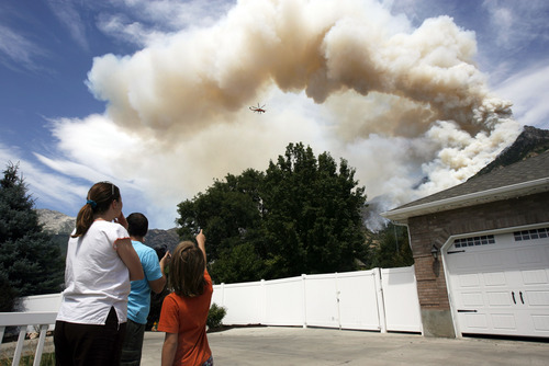 Francisco Kjolseth  |  The Salt Lake Tribune
Emily and Byron Smith along with their son Ammon, 9, watch with concern the fire raging behind their house Wednesday, July 4, 2012, after being allowed back into their home following an evacuation the night before.