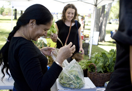 Kim Raff | The Salt Lake Tribune
Dil Dhakak, left, weighs a bag of peas for Melissa Helquist at the New Roots booth at The People's Market, which began its seventh season July 8 with local produce, crafts and entertainment at the International Peace Gardens in Salt Lake City. The market will be open every Saturday from 10 a.m.-3 p.m.