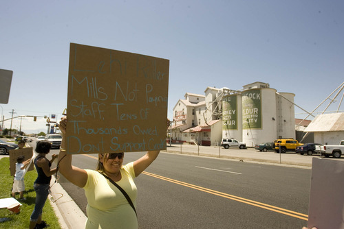 Paul Fraughton | Salt Lake Tribune
Marla Rodriguez, whose husband works at the Lehi Roller Mills, in background, holds up a sign at a small protest Monday, July 9, by employees who contend they have not been paid for their work.