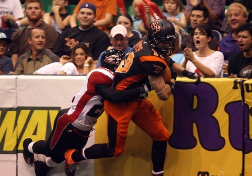 Kim Raff | The Salt Lake Tribune
(right) Utah Blaze player Tysson Poots drags Cleveland Gladiators defensive player Dominic Jones down the field after making a catch during a game at the EnergySolutions Arena in Salt Lake City, Utah on July 13, 2012.