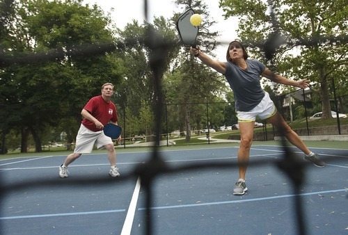 Leah Hogsten  |  The Salt Lake Tribune
Laurel Schwendiman (right) returns a volley while playing with partner Rob Vrooman. Pickleball is played on a badminton court with a lowered net with a perforated plastic baseball (similar to a whiffle ball) and wood or composite paddles. Salt Lake City has added pickleball courts to Reservoir Park due to the growing popularity of the sport.
