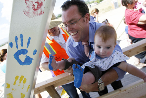Francisco Kjolseth  |  The Salt Lake Tribune
Aaron Thompson uses his son Liam, 8 months, to make his mark on a bridge he was instrumental in recycling with state Rep. Jim Bird of West Jordan. State transportation officials invited people to join in handprint painting Thursday for the pedestrian bridge.
