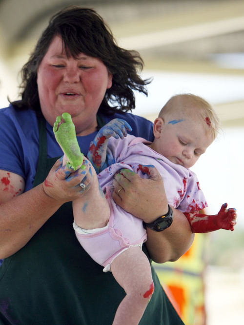 Francisco Kjolseth  |  The Salt Lake Tribune
Diane Patterson gets into the spirit of hand and foot painting a pedestrian bridge with her daughter Adelia, 1. Transportation officials invited the community to help decorate the bridge as a way to help residents feel ownership in it. Patterson saw a post online about the event and thought 