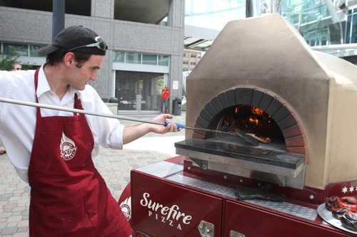Rick Egan  | The Salt Lake Tribune 

Josh Lloyd checks a pizza in the oven of Surefire Pizza, at the Gallivan Plaza, Thursday, July 19, 2012.