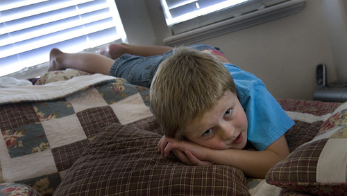 Scott Sommerdorf  |  The Salt Lake Tribune             
Six-year-old Logan Hilton, who is autistic, plays on his parents' bed while watching a kid's video, Friday July 27, 2012. Logan's mother, Michelle Hilton, qualifies for a new pilot program to treat Logan. The problem is she needs to contribute $6,000 to fully benefit.