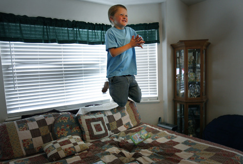 Scott Sommerdorf  |  The Salt Lake Tribune             
Six-year-old Logan HIlton jumps on his parents' bed while watching a video in his Eagle Mountain home, Friday July 27, 2012. His mother, Michelle Hilton, qualifies for a new pilot program to treat Logan. The problem is she needs to contribute $6,000 to fully benefit.