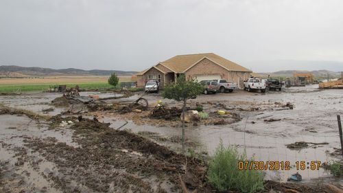 This photo tweeted by the Sanpte County Sheriff's Office shows water swamping a home and lot on July 30, 2012. A thunderstrom dropped water on the area burned in the Wood Hollow Fire.