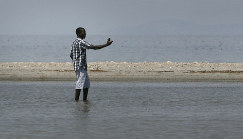 Scott Sommerdorf  |  The Salt Lake Tribune             
Titus Elanyu, a student from Uganda studying at USU, takes a photo of himself as he wades in the shallow water of the Great Salt Lake. Jaimi Butler of Westminster College led a walking tour of the intricate and unique ecology of the Great Salt Lake, Saturday, August 11, 2012.